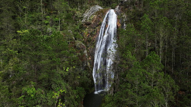 Aerial view of Salto de Aguas Blancas waterfall cascading down a rocky cliff surrounded by dense pine forest in Constanza, La Vega Province, Dominican Republic.