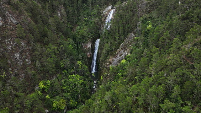 Aerial view of Salto de Aguas Blancas waterfall cascading down rocky cliffs surrounded by dense green forest in Constanza, La Vega Province, Dominican Republic.