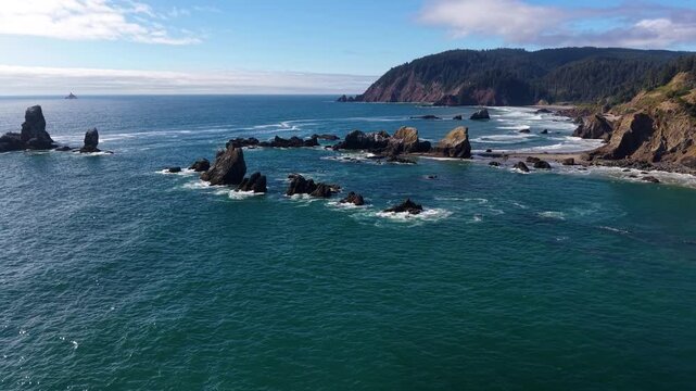 OREGON - 9.2.2026 - Terrific aerial footage swooping towards Oregon's Cannon Beach, with rock formations off the coast a forested cliff in the distance.