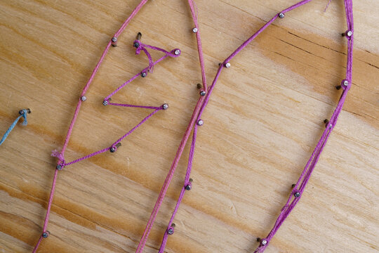 Purple thread on a wooden board for handmade string craft 