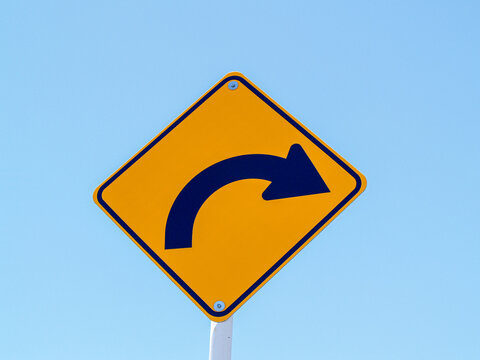 Curving arrow on yellow street sign