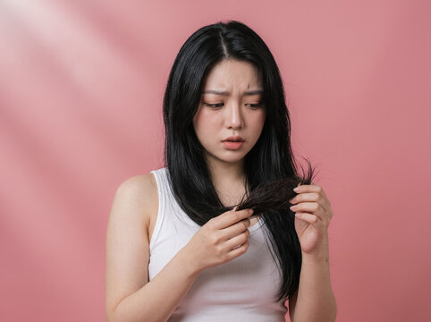 Frustrated woman looking at damaged dry hair and split ends