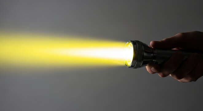 A hand holding a flashlight emitting a bright yellow beam of light