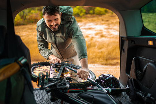 Man loading bicycle into vehicle for an outdoor adventure