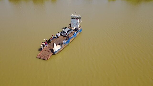 GAMBIA - 12.19.2025 - Good aerial view of a ferry on the Gambia River carrying people and a van.