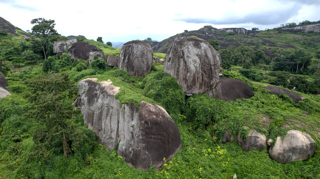 Aerial view of the massive granite rock formations of Idanre Hill covered in lush green vegetation and surrounded by rolling hills in Idanre, Ondo State, Nigeria.