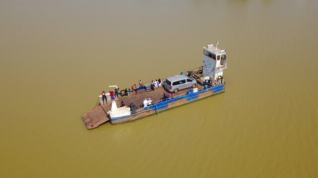 GAMBIA - 12.19.2025 - Great aerial view of people and a van being ferried across the Gambia River.