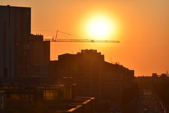 Construction site at sunset with cranes and building silhouettes