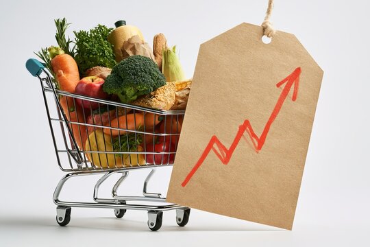 Shopping Cart Full of Groceries Next to Kraft Paper Price Tag with Rising Growth Arrow on White Background Food Inflation Concept