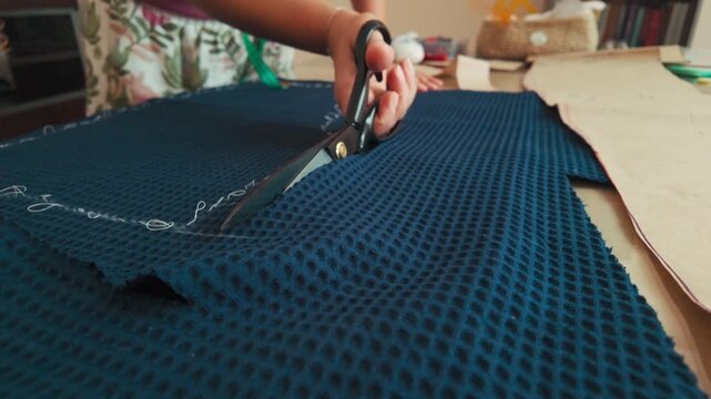 Woman Cuts Fabric with Scissors for a Sewing Project, Crafting Handmade Garments with Precision