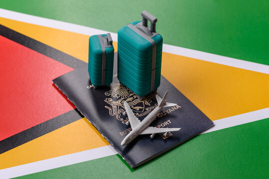Two suitcases on a Guyana flag representing the concept of travel, emigration