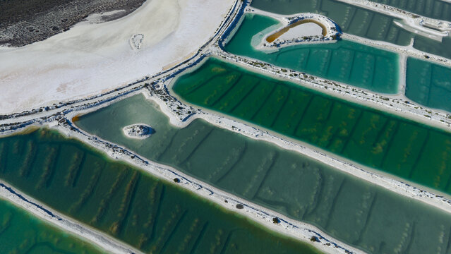 Aerial view of vibrant salt production ponds featuring geometric patterns, turquoise and green water, and white salt crusts in Kalbarri, Western Australia, Australia.