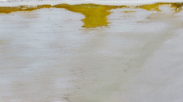 Aerial view of Useless Loop salt mines showing industrial patterns and mineral deposits with yellow and white textures in Kalbarri, Western Australia, Australia.