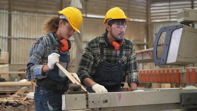 Workers use machinery in a woodworking shop to create products while wearing safety helmets and gloves