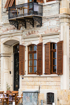 Historic stone house facade with wooden shutters and wrought iron balcony in Aegean coastal town
