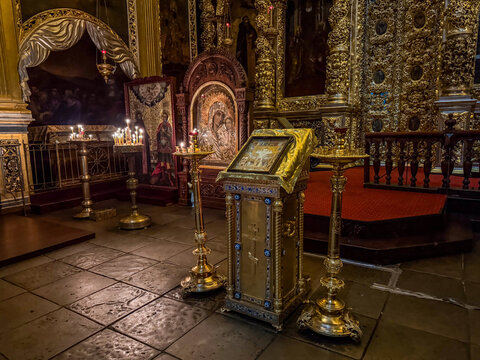 Burning wax candles on golden candlesticks during Christian holidays inside a dark Orthodox church cathedral temple room. Spiritual religious background template with majestic gold iconostasis.  