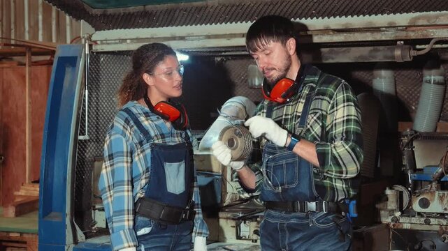 Workers discuss project details while inspecting machinery in a workshop