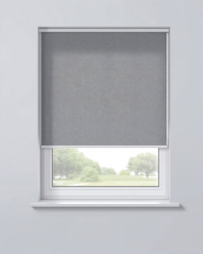 A grey roller blind covering the half of a white window frame, showing a textured fabric surface with a view of green trees in the distance