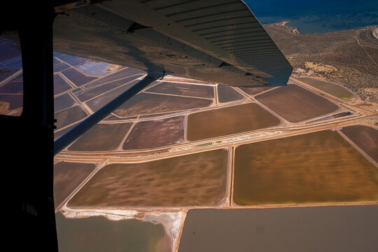 Aerial view of Useless Loop salt lakes showing industrial patterns with brown and yellow water and sand deposits after a storm in Kalbarri, Western Australia, Australia.