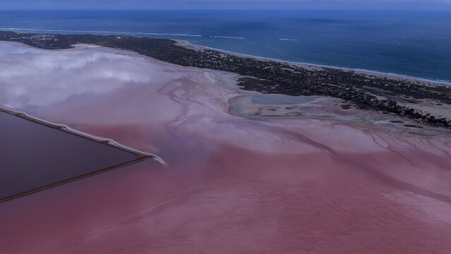 Aerial view of vibrant pink salt lakes and industrial salt pans near Useless Loop, showcasing contrasting colors of sand and water in Kalbarri, Western Australia, Australia.