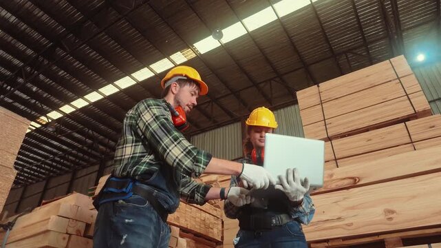 Workers in a warehouse discuss project details while surrounded by stacks of lumber