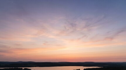 Fototapeta premium Vibrant sunset sky with soft clouds over a dark lake horizon