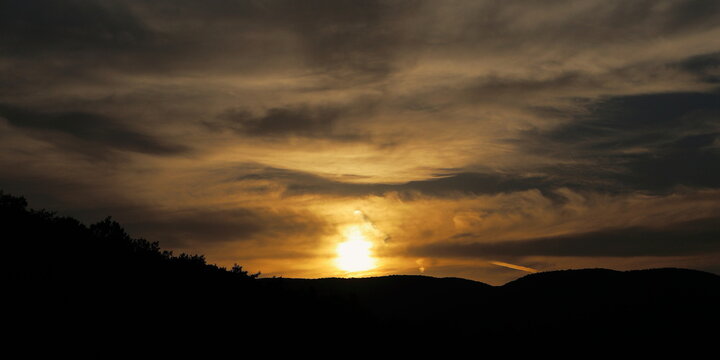 Golden sun rays and dark mountain landscape in the evening