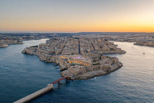 Aerial view of Fort Saint Elmo and the historic city of Valletta at sunset, featuring stone fortifications, narrow streets, and the surrounding Mediterranean Sea in Valletta, Port Region, Malta.