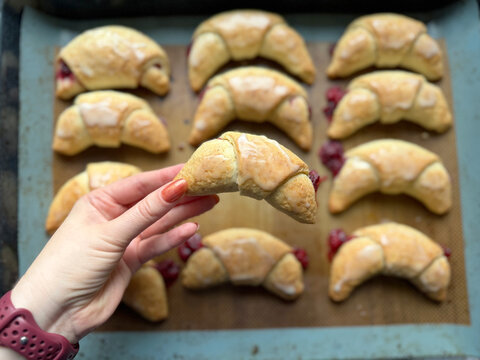 Freshly baked raspberry croissants arranged on baking tray with golden flaky pastry bright berry filling and smooth white glaze Homemade crescent shaped pastries showcase tender layers crisp edges swe