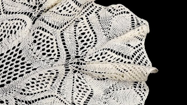 Knitted lace napkin, crochet beige doily lace isolated on black background, crocheted Grandma's doily, detail of handmade embroidery, tablecloth, vintage linen. Flat lay, top view