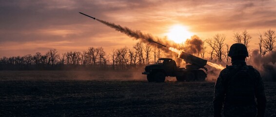 Obraz premium Soldier observing a multiple rocket launcher system releasing rockets in a fiery explosion against a dramatic sunset sky