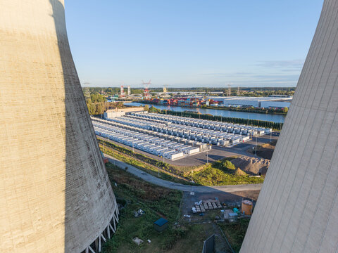 Aerial view of the Cargovil battery energy storage system framed by cooling towers, featuring rows of energy storage containers near a canal in Vilvoorde, Vlaanderen, Belgium.