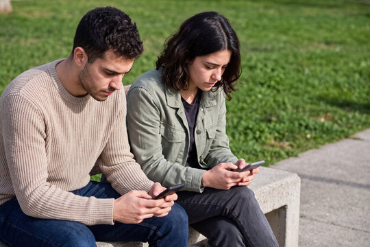 Young couple ignoring each other while looking at their phones