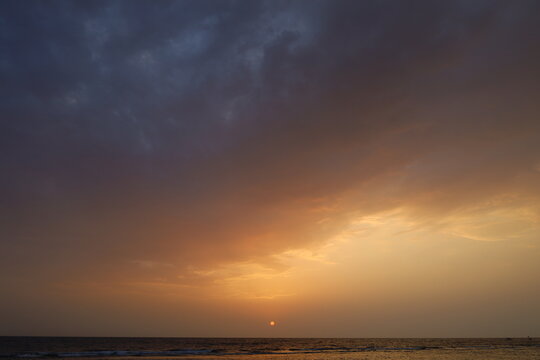 Panoramic view of calm sea horizon under dramatic sunset sky with orange and cloudy gradient, ideal for travel, wellness, and background design