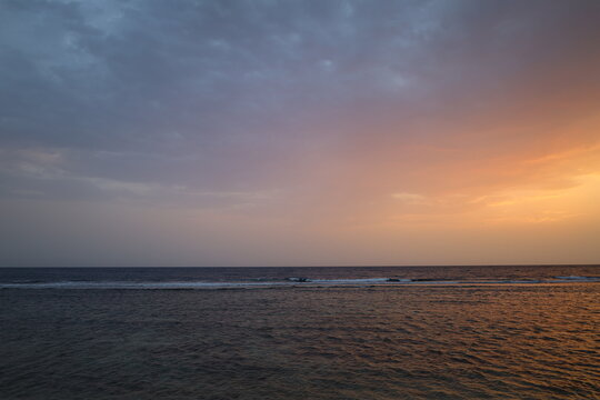Panoramic view of calm sea horizon under dramatic sunset sky with orange and cloudy gradient, ideal for travel, wellness, and background design
