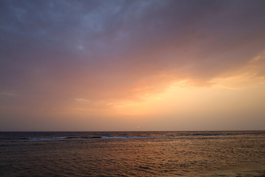 Panoramic view of calm sea horizon under dramatic sunset sky with orange and cloudy gradient, ideal for travel, wellness, and background design