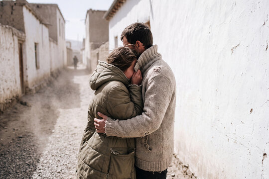 Couple embracing in a dusty alleyway during a windstorm