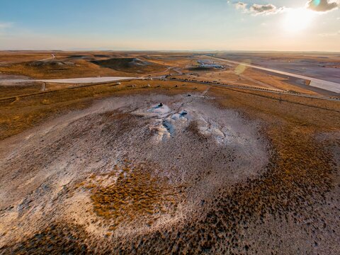 Aerial view of the arid landscape near Sivrihisar, featuring rolling hills, dry vegetation, and a distant road under a warm sunset sky in Sivrihisar, Eskisehir, Turkey.