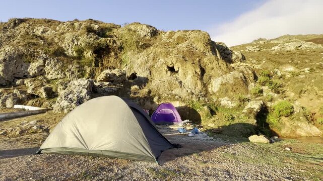 Aknan, Morocco - August 21, 2026: Wide view of tents and camping equipment among rugged mountain rocks.