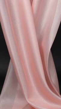 close pink fabric smooth elegant texture fabric appears silky satin like material subtle sheen catches light folds creases fabric create sense movement flow background black making pink color stand