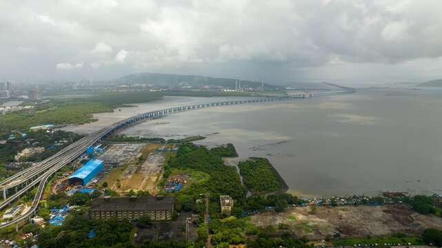 Aerial view of the Atal Bihari Vajpayee Sewri-Nhava Sheva Atal Setu bridge spanning the water with surrounding mangroves and urban infrastructure in Mumbai, Maharashtra, India.