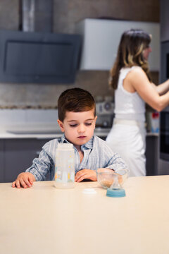 Young boy waiting for breakfast in kitchen with mother