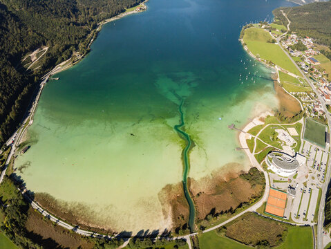 Aerial view of Achen Lake with turquoise waters, surrounding green mountains, and shoreline buildings in Schwaz District, Tyrol, Austria.