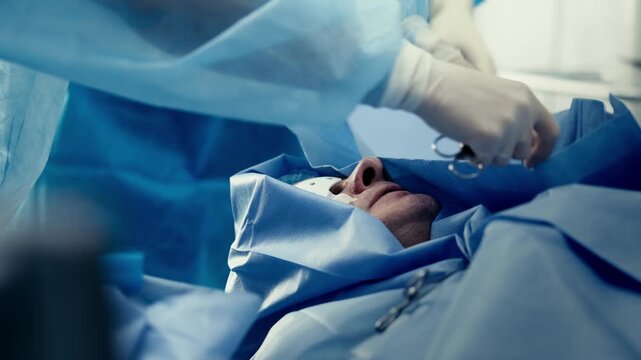 Surgical team covering a patient with sterile drapes before an ophthalmic eye operation.