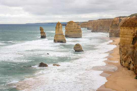 Twelve Apostles sea stacks off a rugged coast with  towering cliffs on a cloudy autumn day