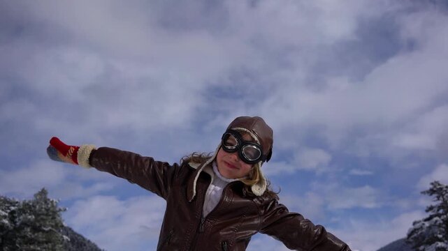 A happy child is playing with a wooden airplane outside in winter. A child with a toy airplane pretends to be a pilot. The concept of childhood dreams and freedom. Slow motion