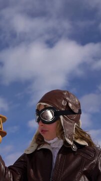 A happy child is playing with a wooden airplane outside in winter. A child with a toy airplane pretends to be a pilot. The concept of childhood dreams and freedom. Slow motion. Vertical video