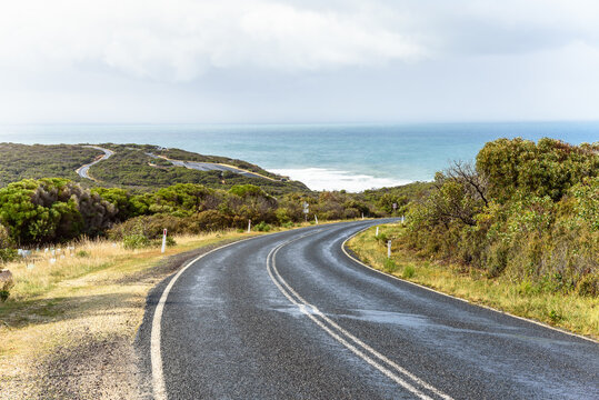 Deserted curvy coast road offering a stunning ocean views  on a sunny autumn day. Storm clouds loom over the ocean. 