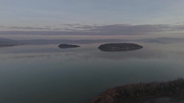 Aerial view of Isola Maggiore surrounded by the calm waters of Lake Trasimeno in Tuoro sul Trasimeno, Umbria, Italy.
