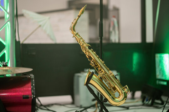 Shiny brass saxophone on stage with green neon backlight illumination